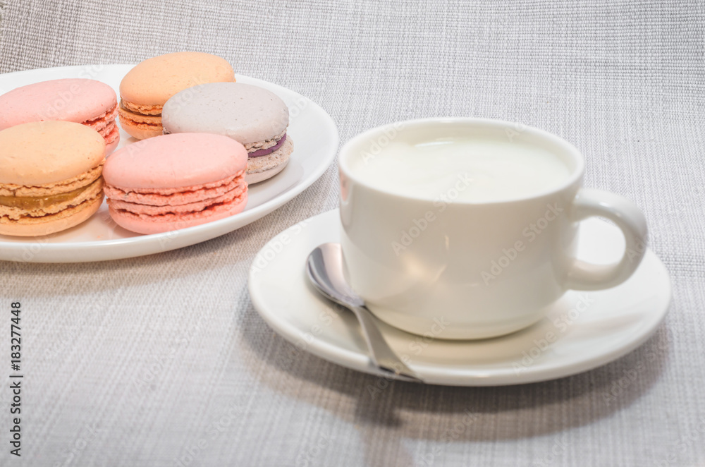 Cake macaroon on the plate and a frothy coffee, close up Cake macaroon on the plate and a frothy coffee, close up