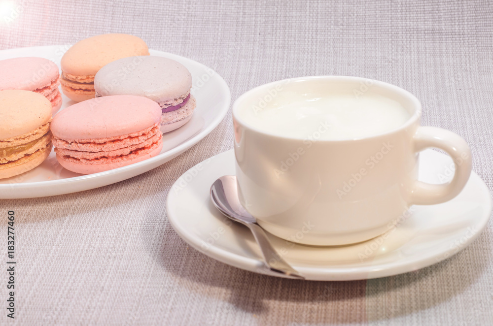 Cake macaroon on the plate and a frothy coffee, close up Cake macaroon on the plate and a frothy coffee, close up