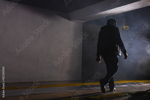 a man walking in the dark in a smoke in a tunnel in front of a bright light