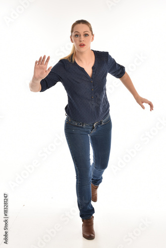 full length portrait of air wearing blue shirt and denim pants, standing pose on white background.