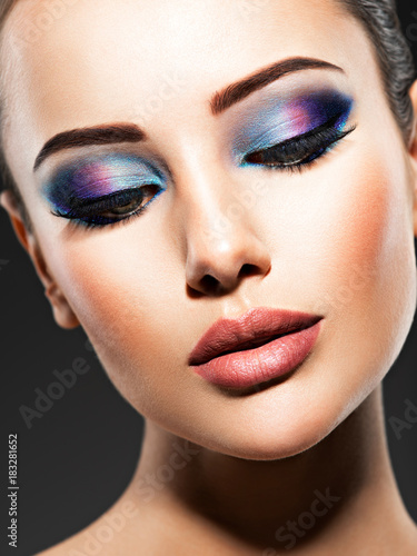 Beautiful face of an young woman with blue makeup of eyes