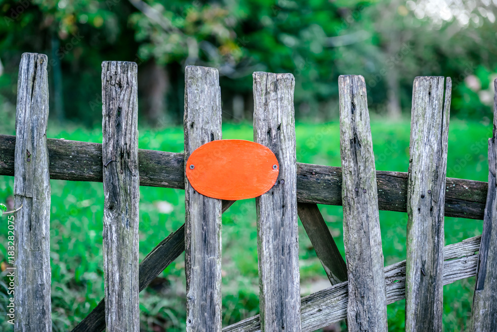 rustic wooden fence holding a blank orange board