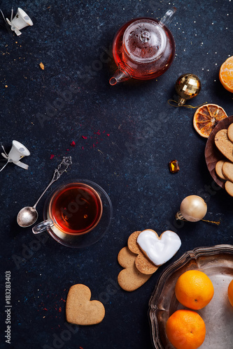 Teatime with heart-shaped ginger cookies and tangerines. Christmas background with festive decoration. Vertical composition