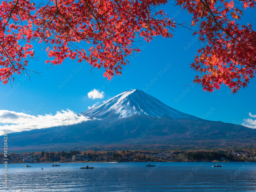 Fuji mountain with red maple and the fishermen are fishing on boat in the lake.