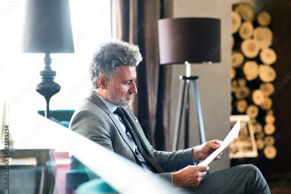 Fototapeta premium Mature businessman reading in a hotel lounge.