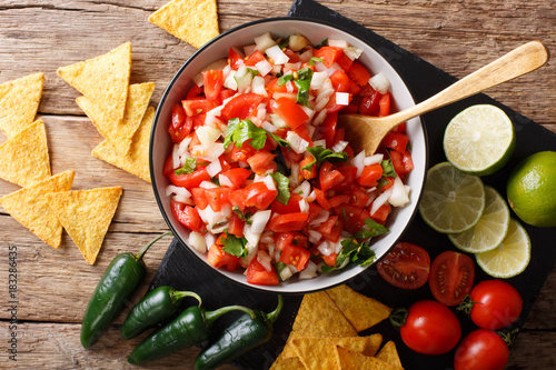 Homemade spicy pico de gallo close-up in a bowl and nachos. horizontal top view