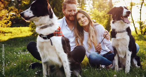 Beautiful couple cuddling and walking dogs outdoors