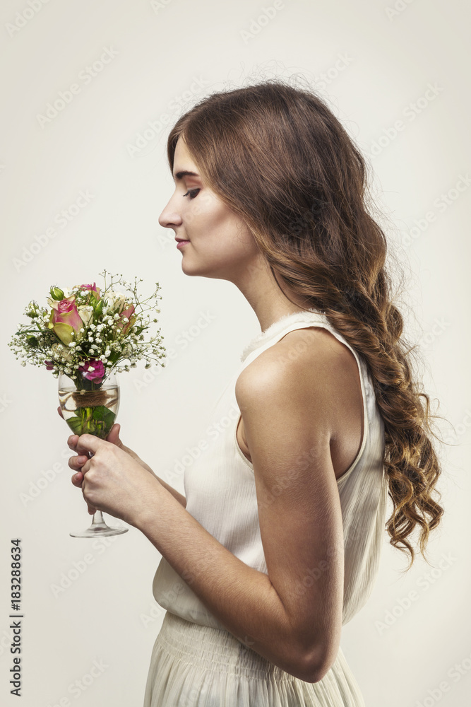 Girl with long hair and a bouquet of flowers in a glass Girl with long hair and a bouquet of flowers in a glass