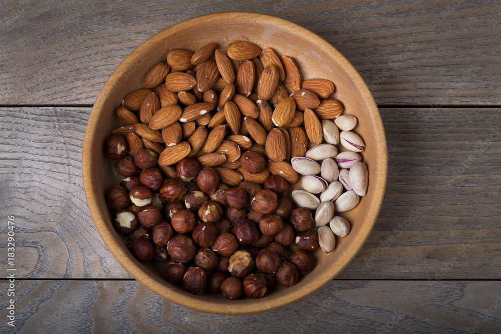 Fototapeta premium Pistachio, hazelnut, almonds in wooden plate