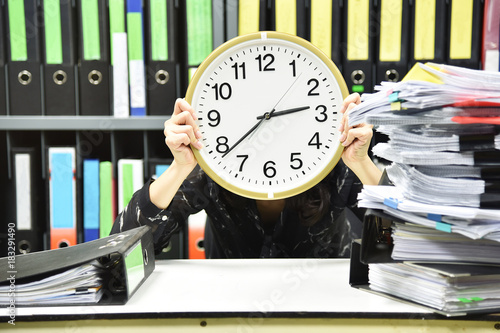 Office worker holding a clock, Working overtime and lot of work, Time management concept. photo