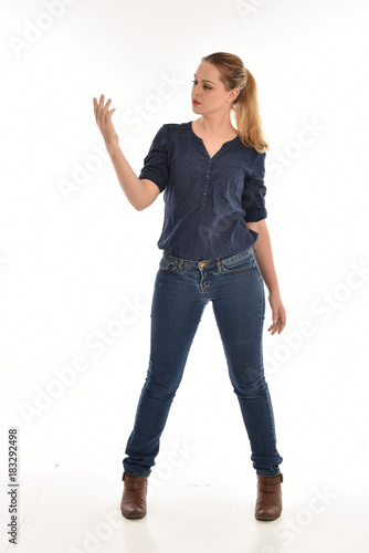 full length portrait of air wearing blue shirt and denim pants, standing pose on white background.