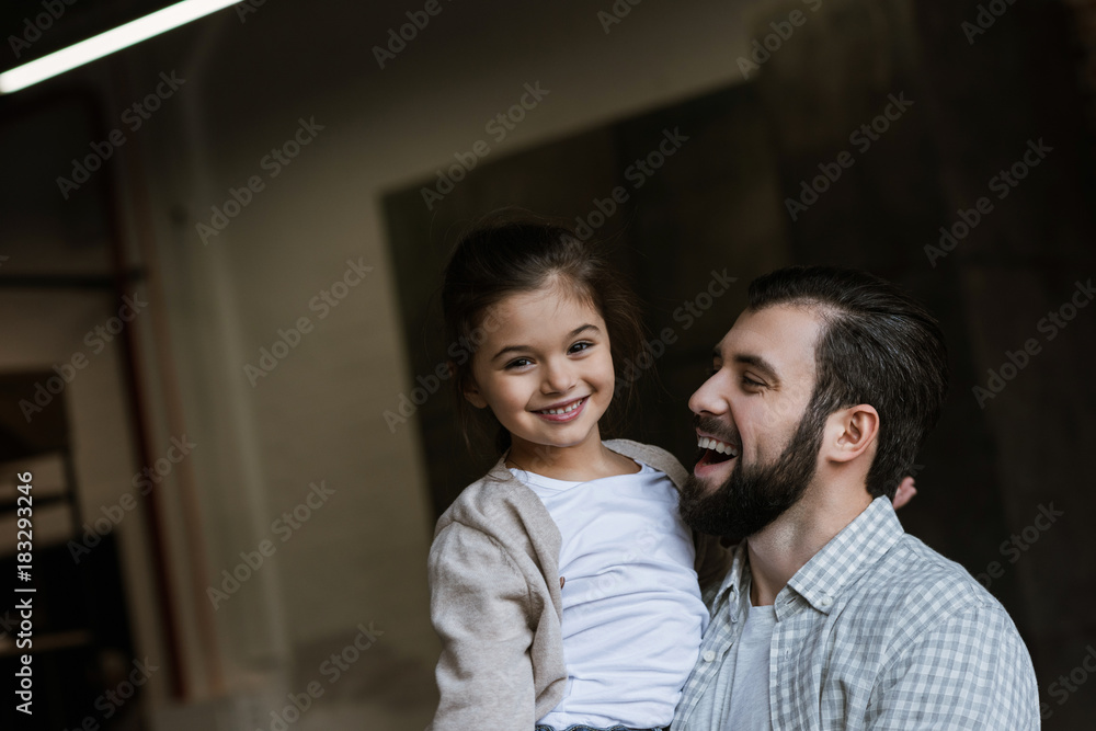cheerful father and daughter hugging and looking at camera at home cheerful father and daughter hugging and looking at camera at home