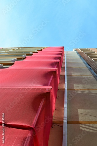 Baugerüst mit besonderem roten Akzent vor stahlblauem Himmel photo