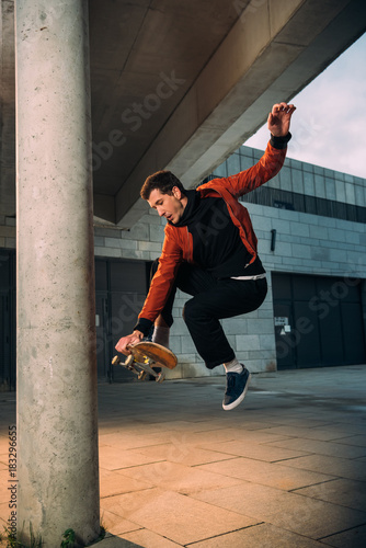 stylish young skateboarder performing jump trick in urban location