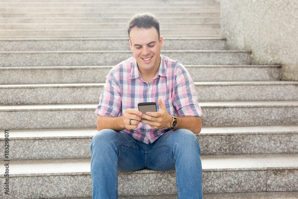 Smiling Man Using Smartphone on City Stairway