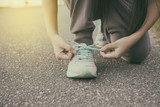 Female runner tying her shoes preparing for jogging outside .Young girld runner getting ready for training. Sport lifestyle