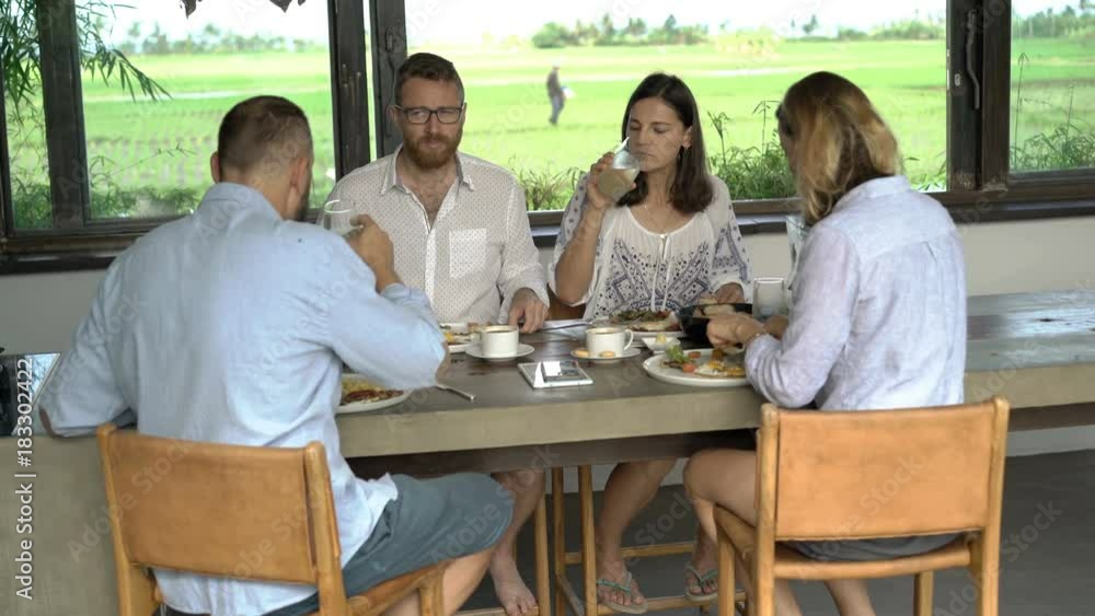 Friends talking and eating meal sitting by table at home
Friends talking and eating meal sitting by table at home