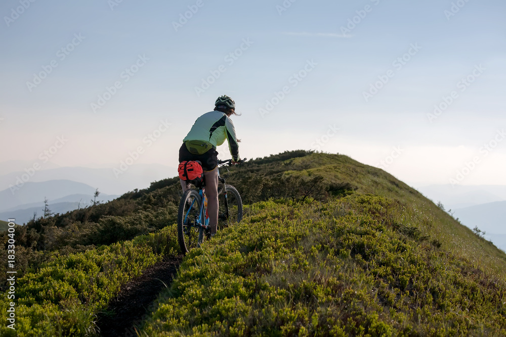 Woman rides bicycle up in the mountains Woman rides bicycle up in the mountains