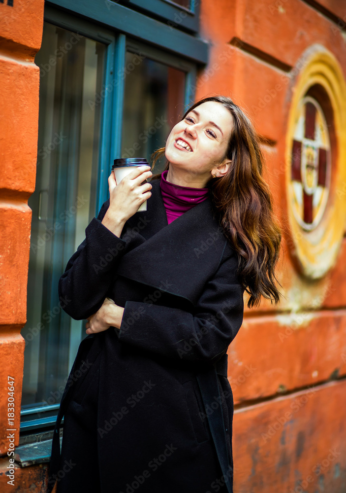 Obraz premium A sincere girl stands with coffee in her hands