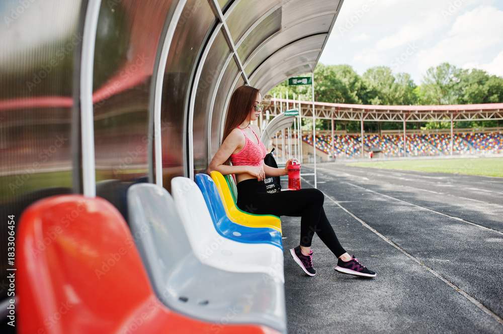 Fitness sporty girl in sportswear at stadium outdoor sports. Happy sexy woman at coach tribune.