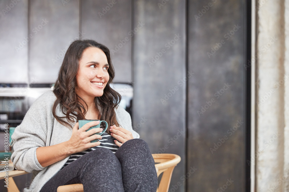 Lächelnde kurvige Frau mit Tasse Tee oder Kaffee