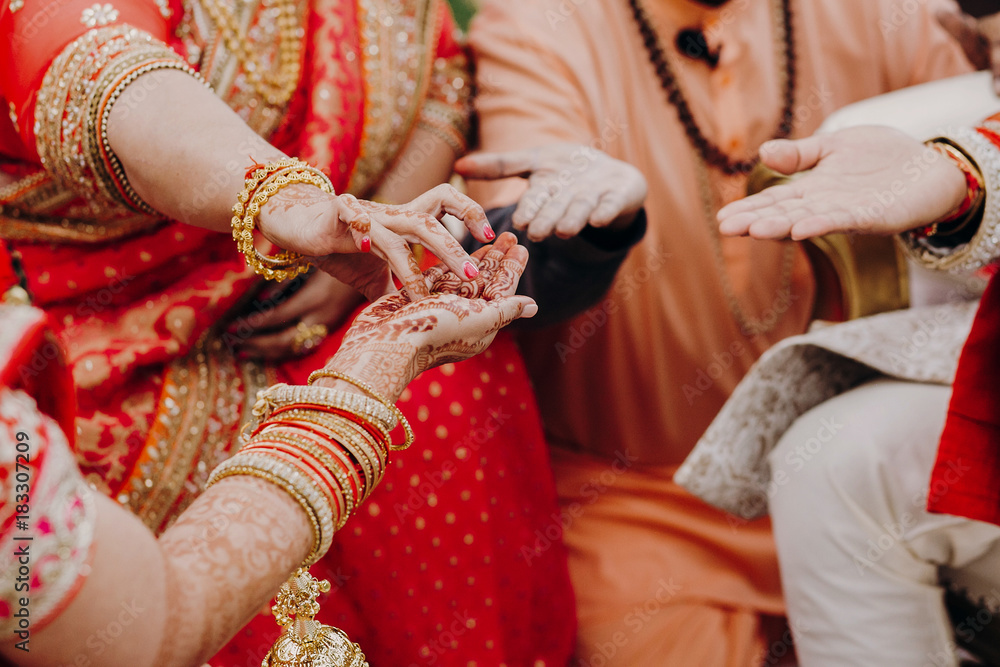 Indian newlyweds take something from mother's hands covered with henna tattoos