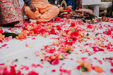 Pink and orange flowers lie before the feet of Indian wedding couple during the Saptapadi wedding ceremony