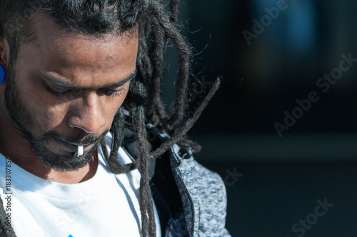 Valokuva black man with dreadlocks with rolling tobacco nozzle in his mouth