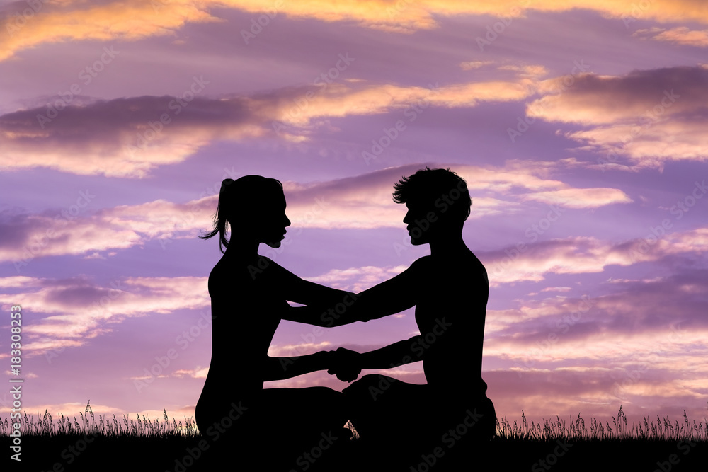 man and woman doing yoga at sunset