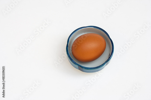 Top view of fresh egg in white small bowl isolated on white background. (Selective focus)