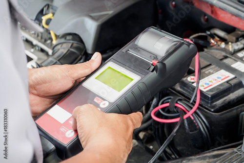 mechanic use voltmeter checking voltage of car battery in car service centre