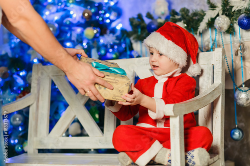 boy in santa costume receives christmas gift photo