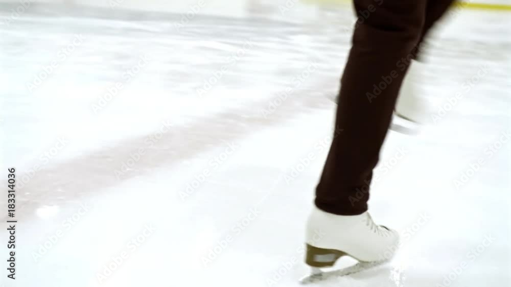 Low section of legs of female professional figure skater spinning on ice rink Low section of legs of female professional figure skater spinning on ice rink