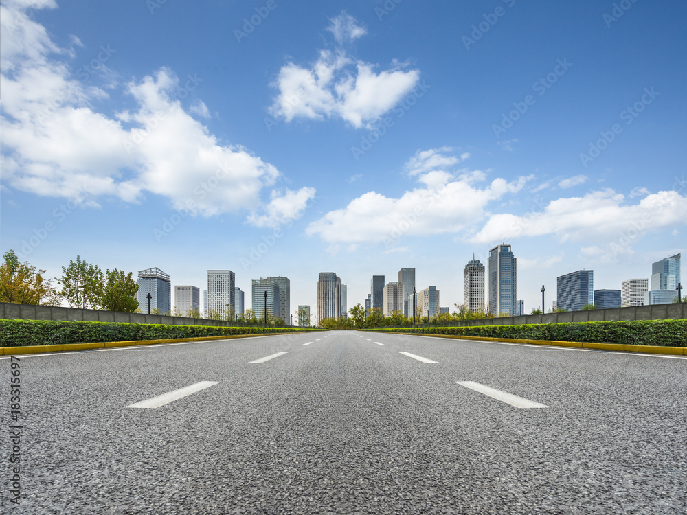 city road through modern buildings against blue sky city road through modern buildings against blue sky