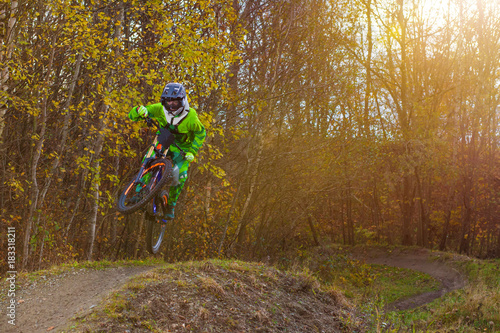 Radfahrer springt über Hügel auf Downhill Strecke im Gegenlicht mit Blendenflecken