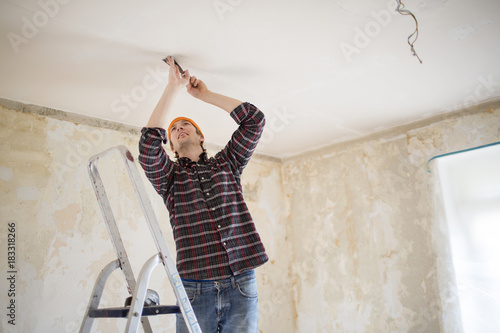 Man scraping off plaster from ceiling