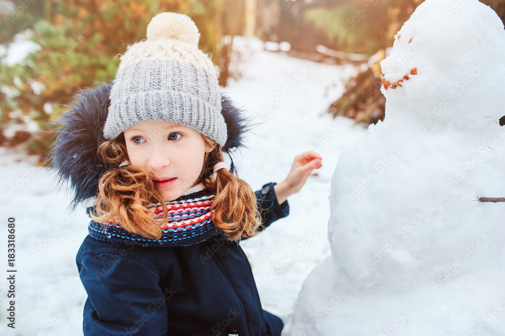 happy kid girl making snow man on Christmas vacations on backyard. Winter outdoor activities for kids. happy kid girl making snow man on Christmas vacations on backyard. Winter outdoor activities for kids.