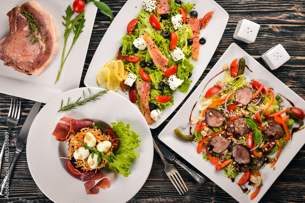 Food. Salads from vegetables, salmon, veal, steak, meat. On a wooden background. Top view. Free space for text. Food. Salads from vegetables, salmon, veal, steak, meat. On a wooden background. Top view. Free space for text.