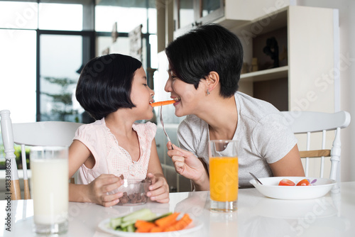 Young Asian mother and daughter eating together at home.