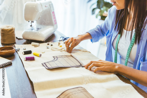 cropped image of smiling seamstress measuring pattern at table