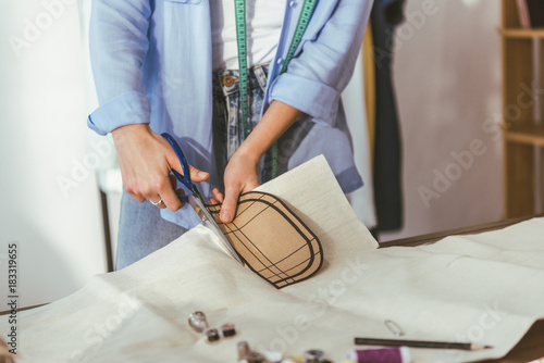 cropped image of seamstress cutting fabric with scissors
