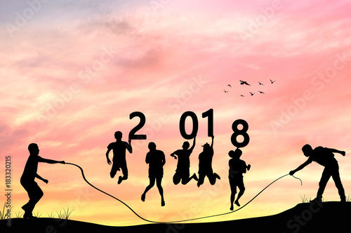 Silhouette of grooup people rope jumping and holding words 2018 with in twilight, teamwork , team and Happy new year  concept . photo