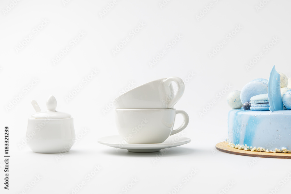 blue tasty cake on chopping board with tea cups isolated on white blue tasty cake on chopping board with tea cups isolated on white