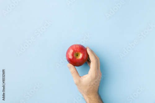 top view of hand holding apple isolated on blue