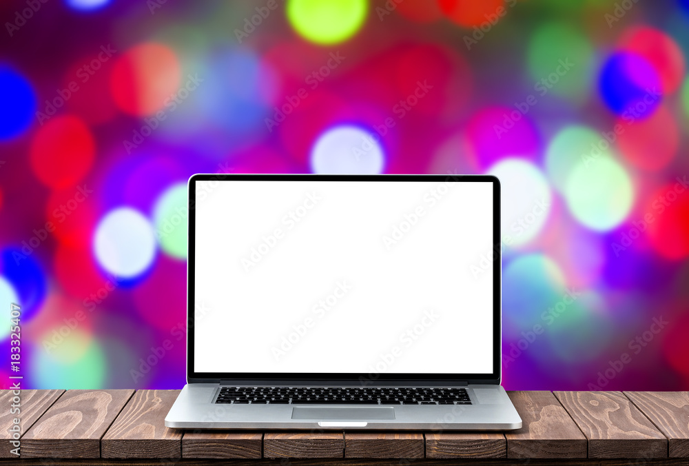 Modern laptop with empty white screen on wooden table against blurred Christmas lights background Modern laptop with empty white screen on wooden table against blurred Christmas lights background