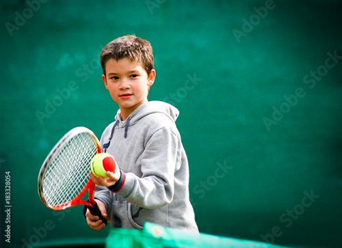 Little tennis player on a blurred green background.