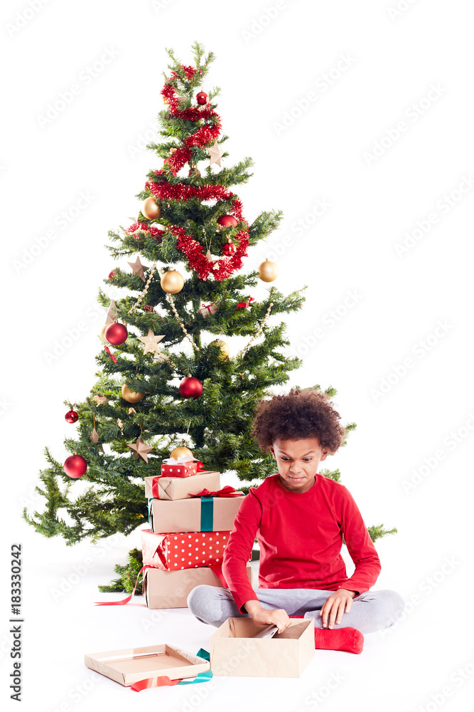 Portrait of cute mixed race little boy unpacking gifts near Christmas tree and taking digital tablet out of box Portrait of cute mixed race little boy unpacking gifts near Christmas tree and taking digital tablet out of box