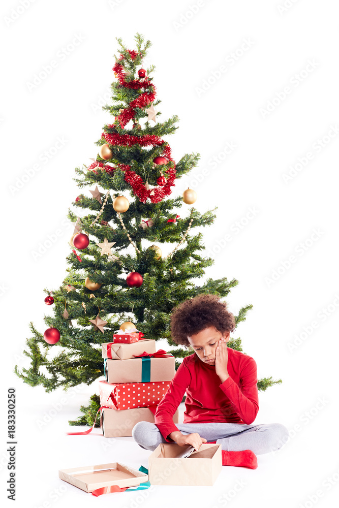 Portrait of cute mixed race little boy unpacking gifts near Christmas tree and taking digital tablet out of box