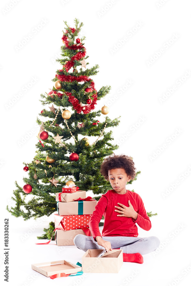 Portrait of cute mixed race little boy unpacking gifts near Christmas tree and taking digital tablet out of box Portrait of cute mixed race little boy unpacking gifts near Christmas tree and taking digital tablet out of box