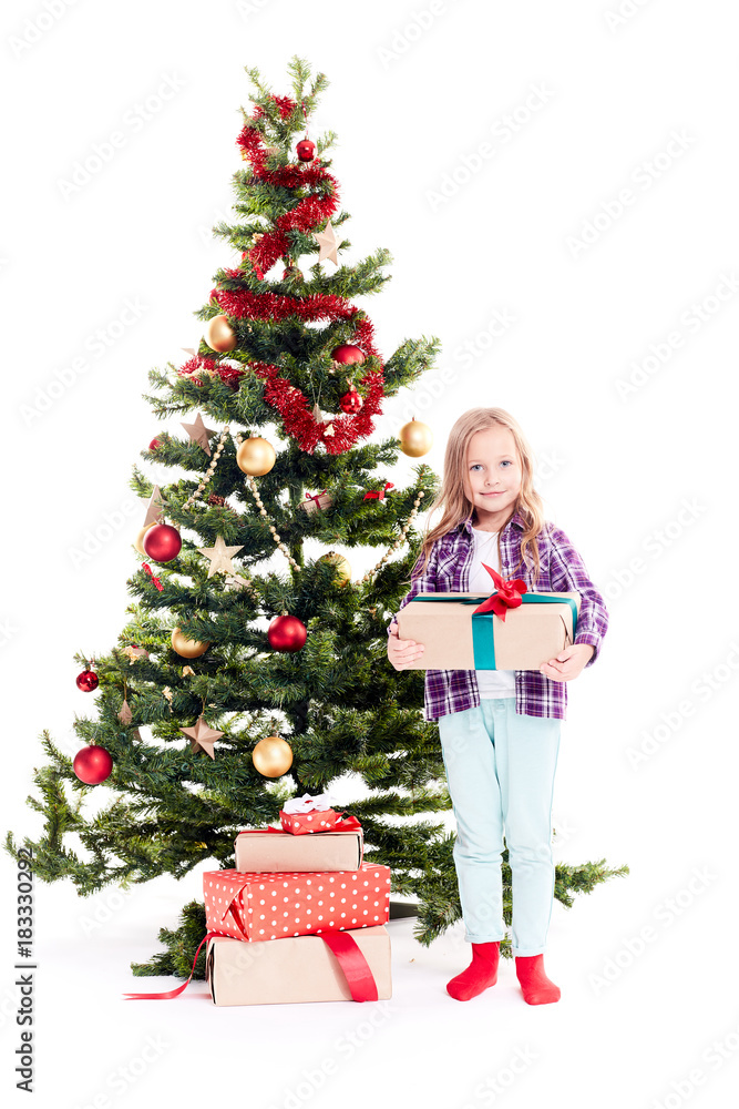 Portrait of little girl standing near Christmas tree with gift box in her hands on white background Portrait of little girl standing near Christmas tree with gift box in her hands on white background
